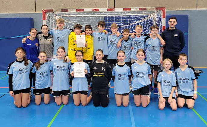 Gruppenbild der WRG-Handballmannschaften (Jungen und Mädchen) vor einem Handballtor in der Sporthalle