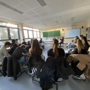 Klassenraum, Stuhlkreis, digitale Päsentation, vorne Moderatorin