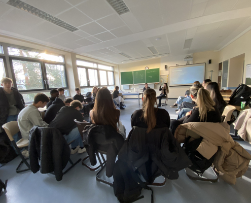 Klassenraum, Stuhlkreis, digitale Päsentation, vorne Moderatorin