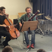 2 Musiker, ein Fagottist und ein Cellist spielen auf einem Podest in einem Musiksaal