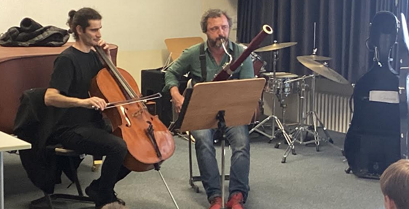 2 Musiker, ein Fagottist und ein Cellist spielen auf einem Podest in einem Musiksaal