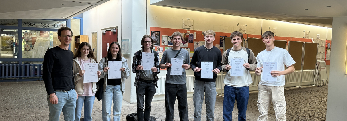 Gruppenbild des Mathe-LKs mit Urkunden vor der Uni in Landau
