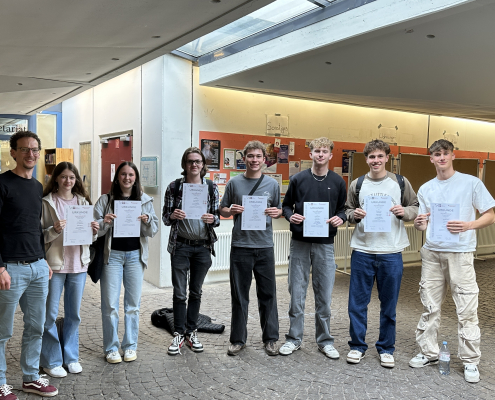 Gruppenbild des Mathe-LKs mit Urkunden vor der Uni in Landau