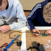 Zwei Jungen beugen sich über eine Platine und löten