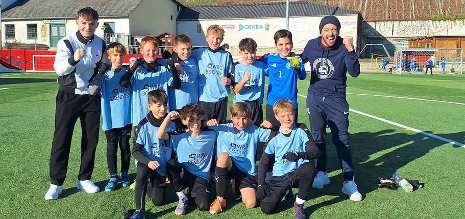 Gruppenbild auf Sportplatz: 10 Fußballer und 2 Betreuer