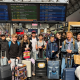 eine Gruppe von 15 Schülerinnen und Schülern mit Gepäck wartet in einem französischem Bahnhof